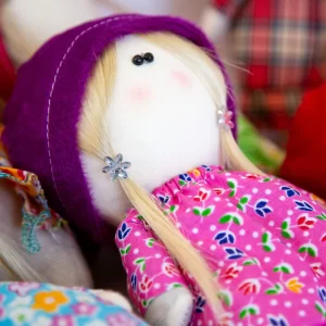 the doll in purple dress and hat with blonde hair color